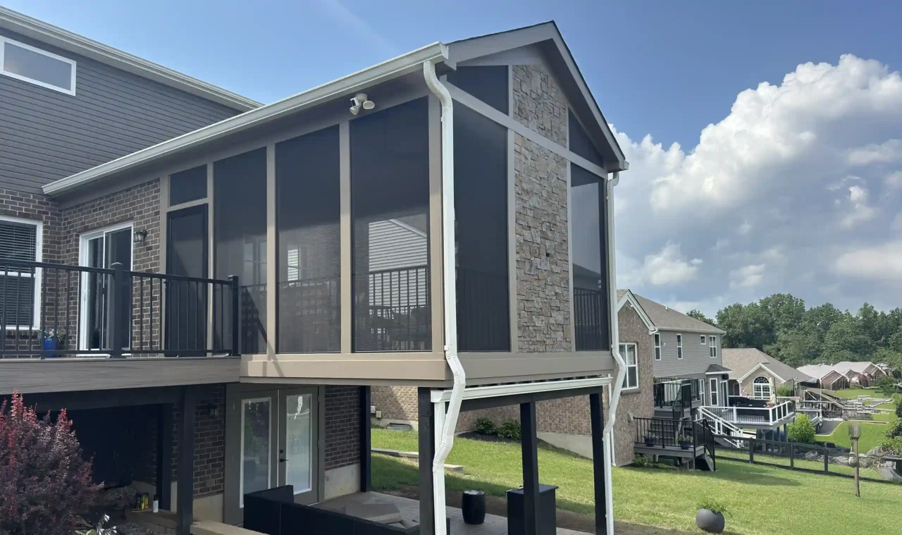 Custom screened-in porch with stone accents and black aluminum railing on a multi-level home.