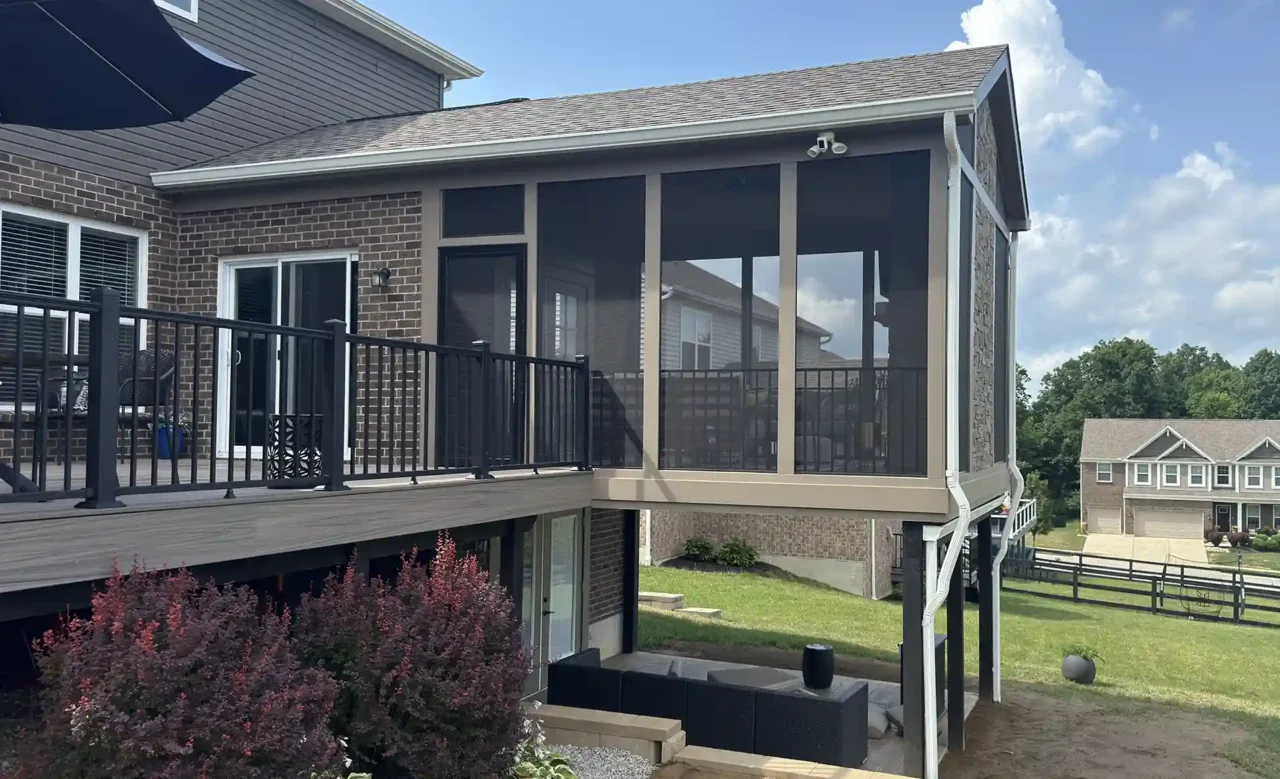 View of a screened-in porch from an angled perspective, featuring black aluminum railing and stone accents.