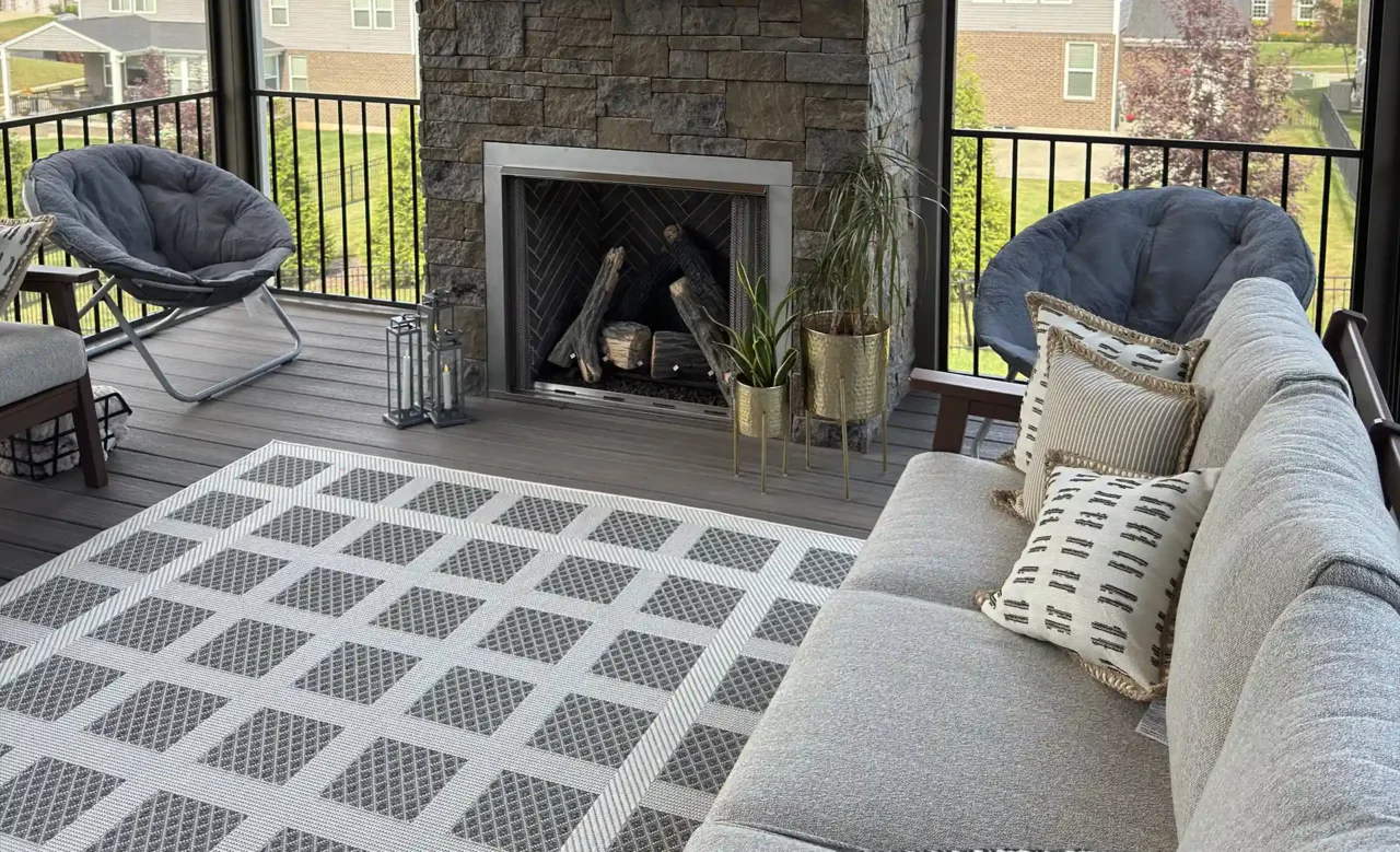 Screened-in porch featuring a stone fireplace with a TV mounted above, a rug, and seating, with large windows