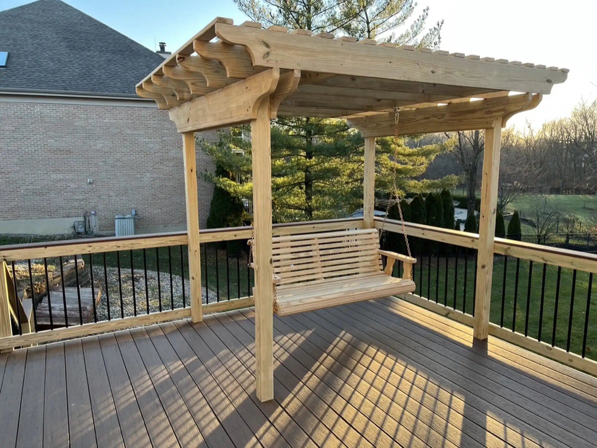 pergola cost in cincinnati Natural wood pergola over a hanging wooden porch swing on a composite deck with black metal baluster railing